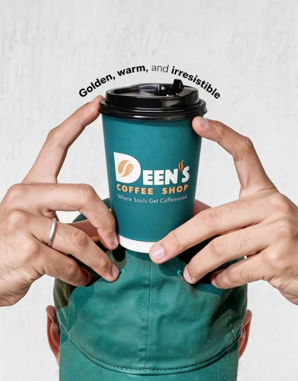 A Deen's teal coffee cup held up with both hands